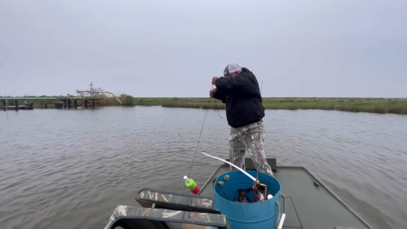 A man is jug fishing on a boat